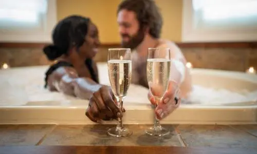 Coppia che beve champagne nella vasca da bagno.