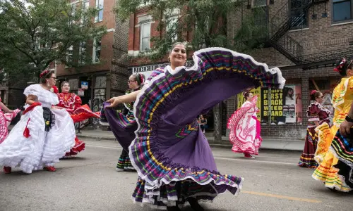 Ballerini di folklore che volteggiano in abiti tradizionali durante una sfilata di strada a Chicago.