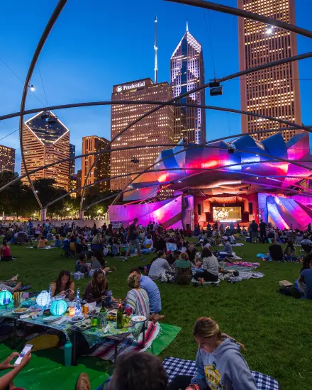 Una folla si è radunata sul prato per un concerto serale al Millennium Park di Chicago.