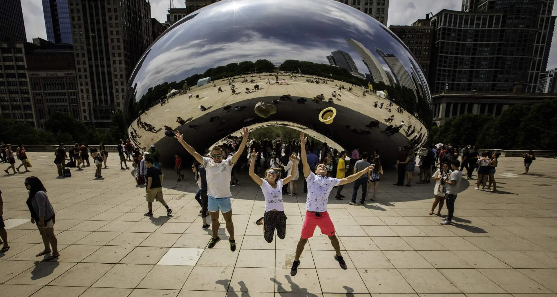Tre persone che saltano in aria davanti al punto di riferimento The Bean a Chicago