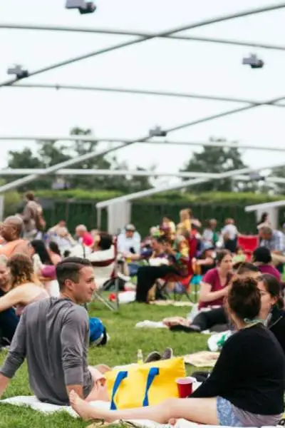 Un folto pubblico seduto sull'erba all'esterno del Pritzker Pavillion