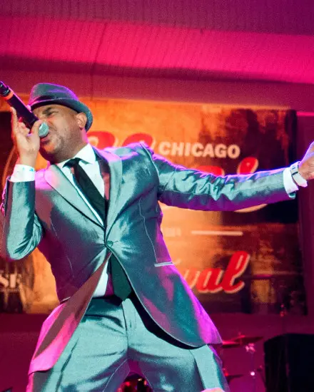 Un cantante blues su un palco con un elegante completo metallico che intona una canzone