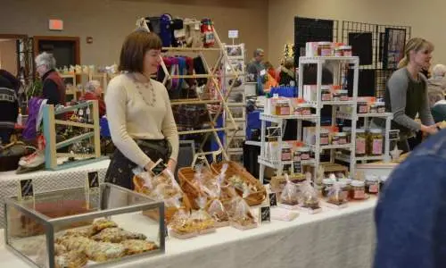 Una donna in piedi dietro a prodotti da forno su un tavolo