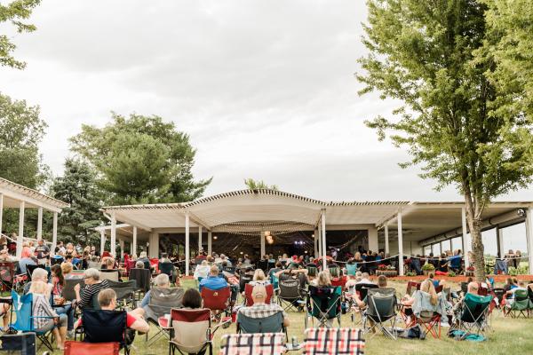 Persone su sedie da giardino davanti al palco musicale