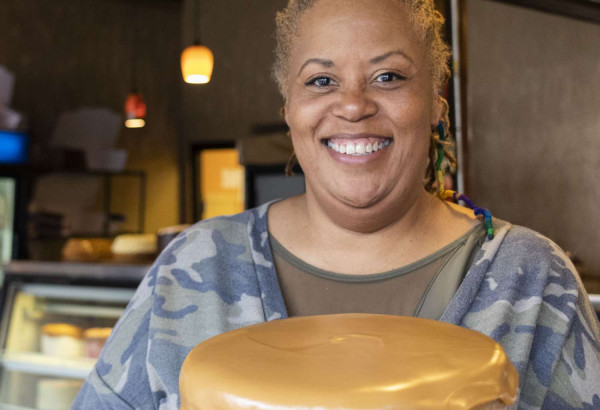 Una donna sorridente con in mano una torta
