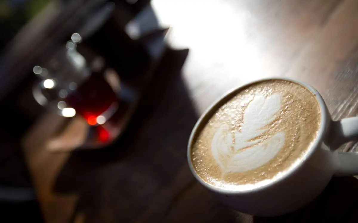 Una tazza di caffè con una perfetta foglia di latte art realizzata con la schiuma di latte.