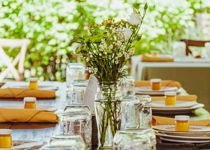 Una foto di piatti allineati lungo un tavolo da pranzo con dei fiori al centro
