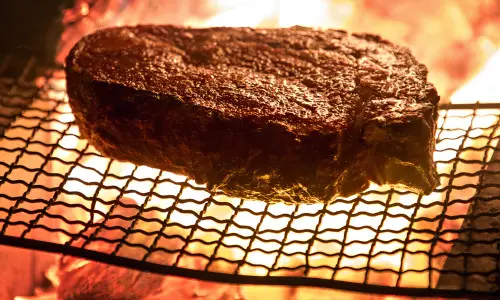 Una bistecca di grandi dimensioni viene cotta su una griglia a fiamma libera.