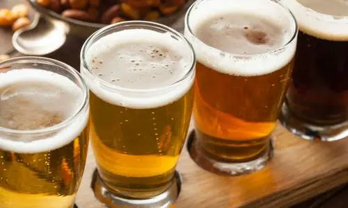 Quattro bicchieri di birra su un vassoio di legno