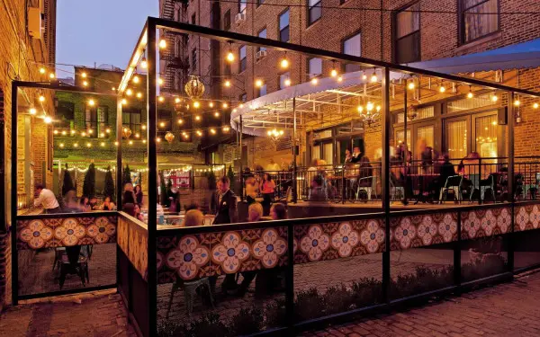 Gli avventori cenano nel patio all'aperto sotto le luci delle lampadine