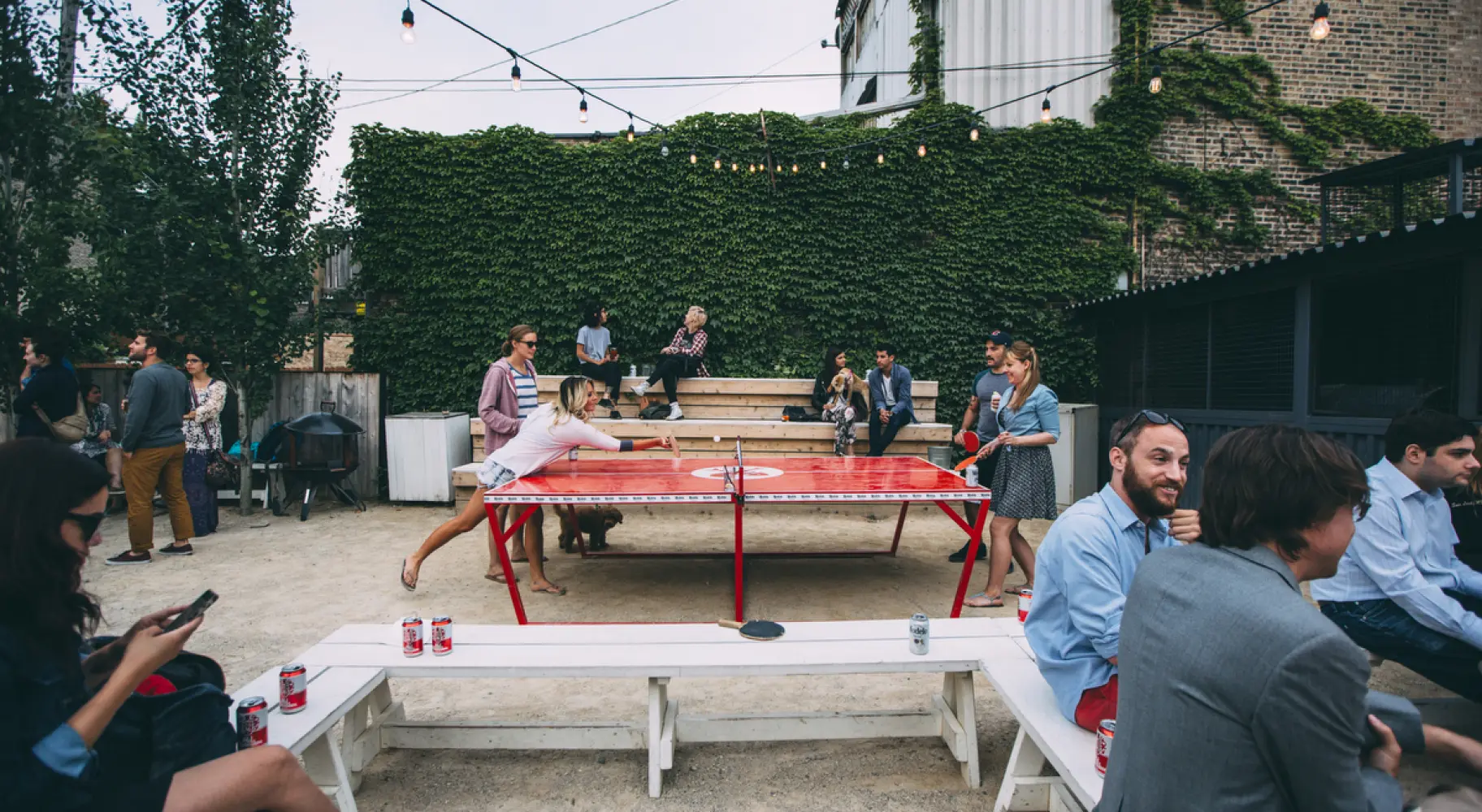 Avventori bevono birre e giocano a ping pong all'aperto