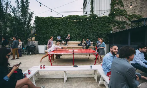 Avventori bevono birre e giocano a ping pong all'aperto