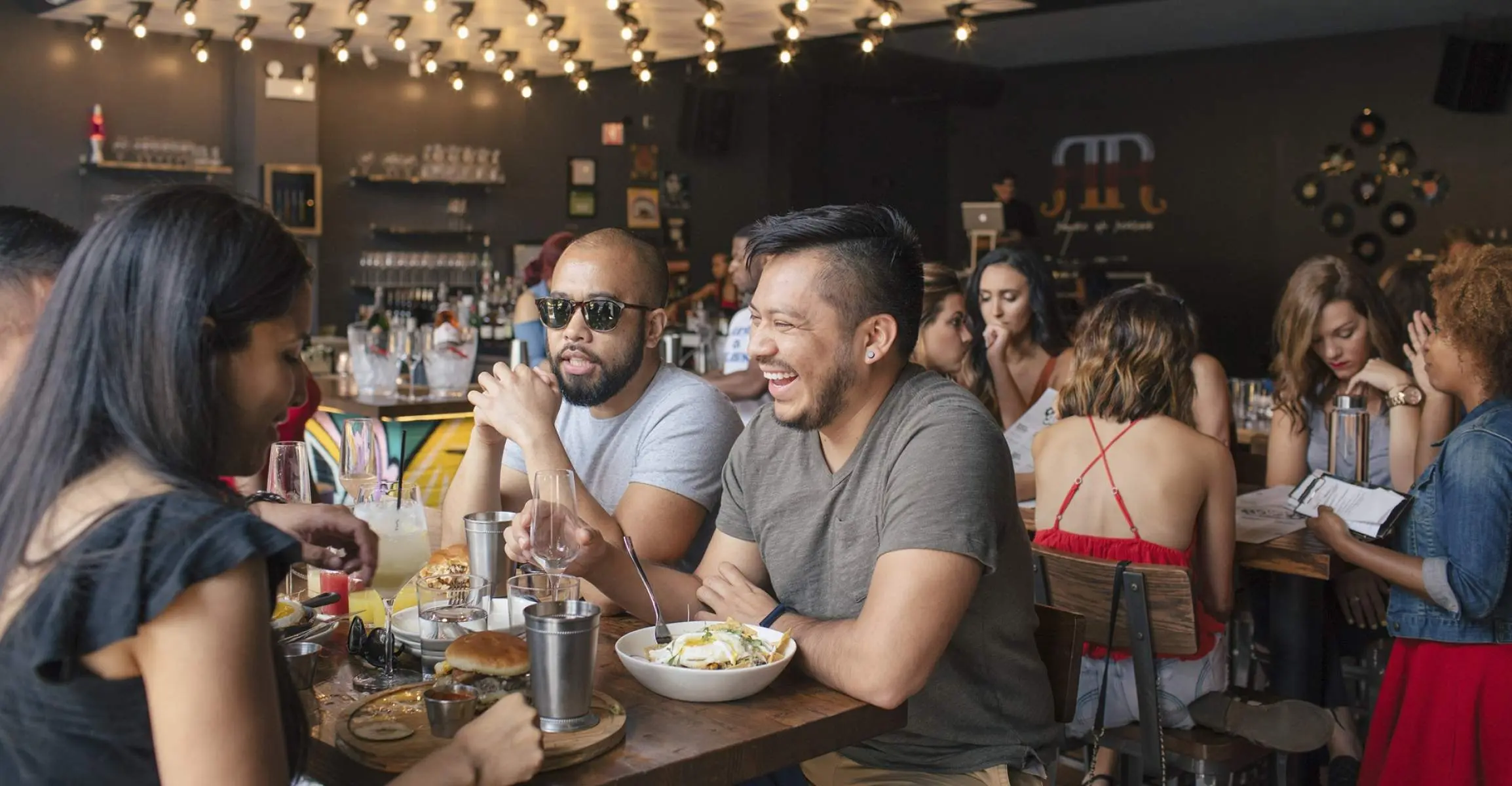 Tre amici che consumano un brunch all'interno di un bar e ristorante affollato