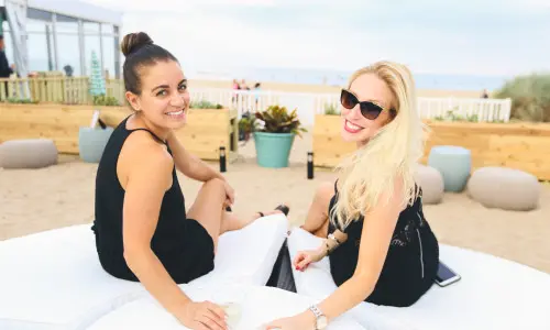 Due donne che bevono un drink su un lettino da spiaggia