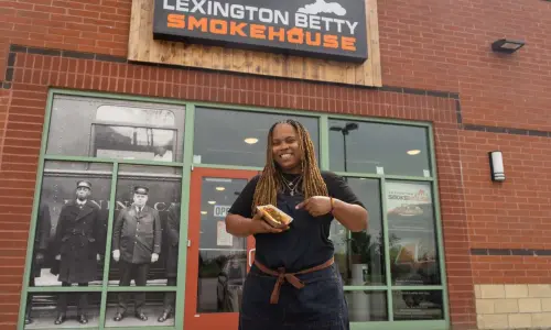 Una donna con in mano un hotdog davanti alla Lexington Betty Smokehouse.