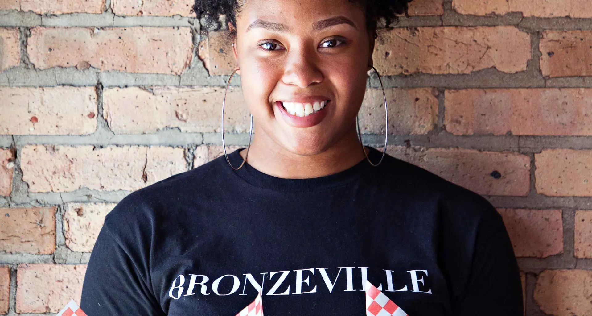 Donna con cibo in mano davanti a un muro di mattoni