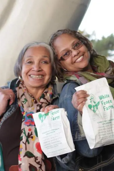 Due donne con in mano sacchetti di pollo fritto della White Fence Farm