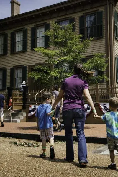 Una madre e dei bambini camminano verso la casa di Lincoln presso il Lincoln Home Historic Site di Springfield