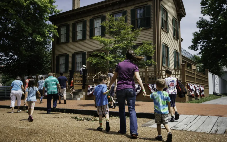 Una madre e dei bambini camminano verso la casa di Lincoln presso il Lincoln Home Historic Site di Springfield