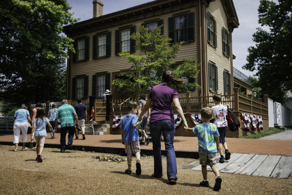 Una madre e dei bambini camminano verso la casa di Lincoln presso il Lincoln Home Historic Site di Springfield