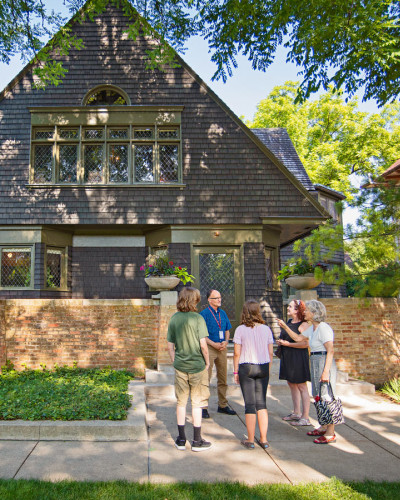 Una guida parla a un gruppo di visitatori sul marciapiede davanti alla casa e allo studio di Frank Lloyd Wright a Oak Park