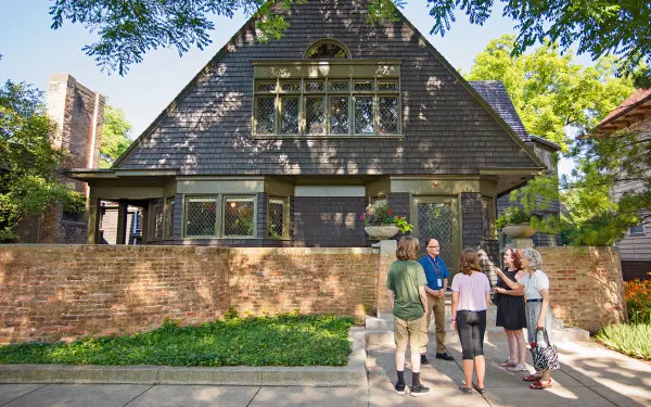 Una guida parla a un gruppo di visitatori sul marciapiede davanti alla casa e allo studio di Frank Lloyd Wright a Oak Park