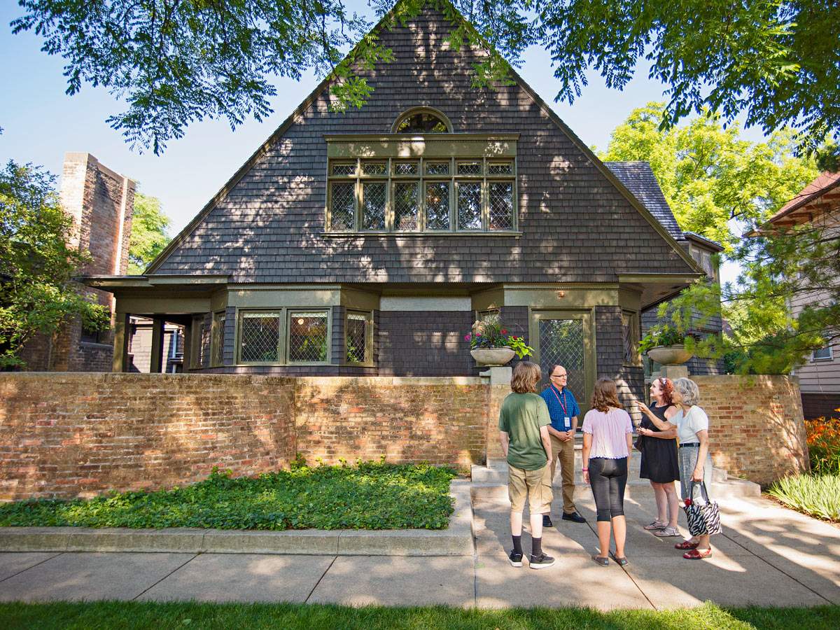 Una guida parla a un gruppo di visitatori sul marciapiede davanti alla casa e allo studio di Frank Lloyd Wright a Oak Park