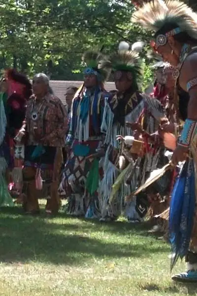 Un gruppo di uomini in abiti nativi americani su una radura erbosa tra gli alberi