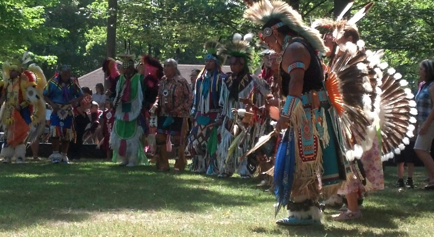 Un gruppo di uomini in abiti nativi americani su una radura erbosa tra gli alberi