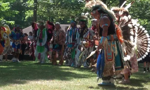 Un gruppo di uomini in abiti nativi americani su una radura erbosa tra gli alberi