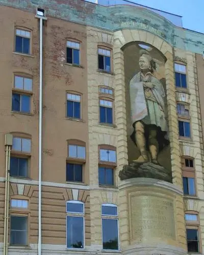 Un grande murale di Blackhawk, alto tre piani, sulla facciata di un edificio in mattoni.