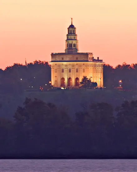 Un tempio con le luci accese dietro gli alberi e un fiume