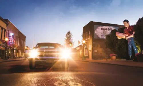 Un'auto d'epoca con i fari accesi, accanto alla gigantesca statua di Paul Bunyon ad Atlanta