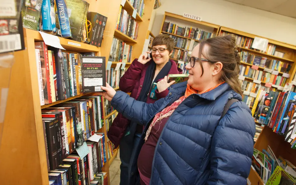 Donne in libreria che guardano uno scaffale di libri