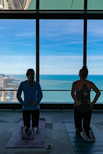 Quattro persone inginocchiate su tappetini da yoga che guardano la costa di Chicago
