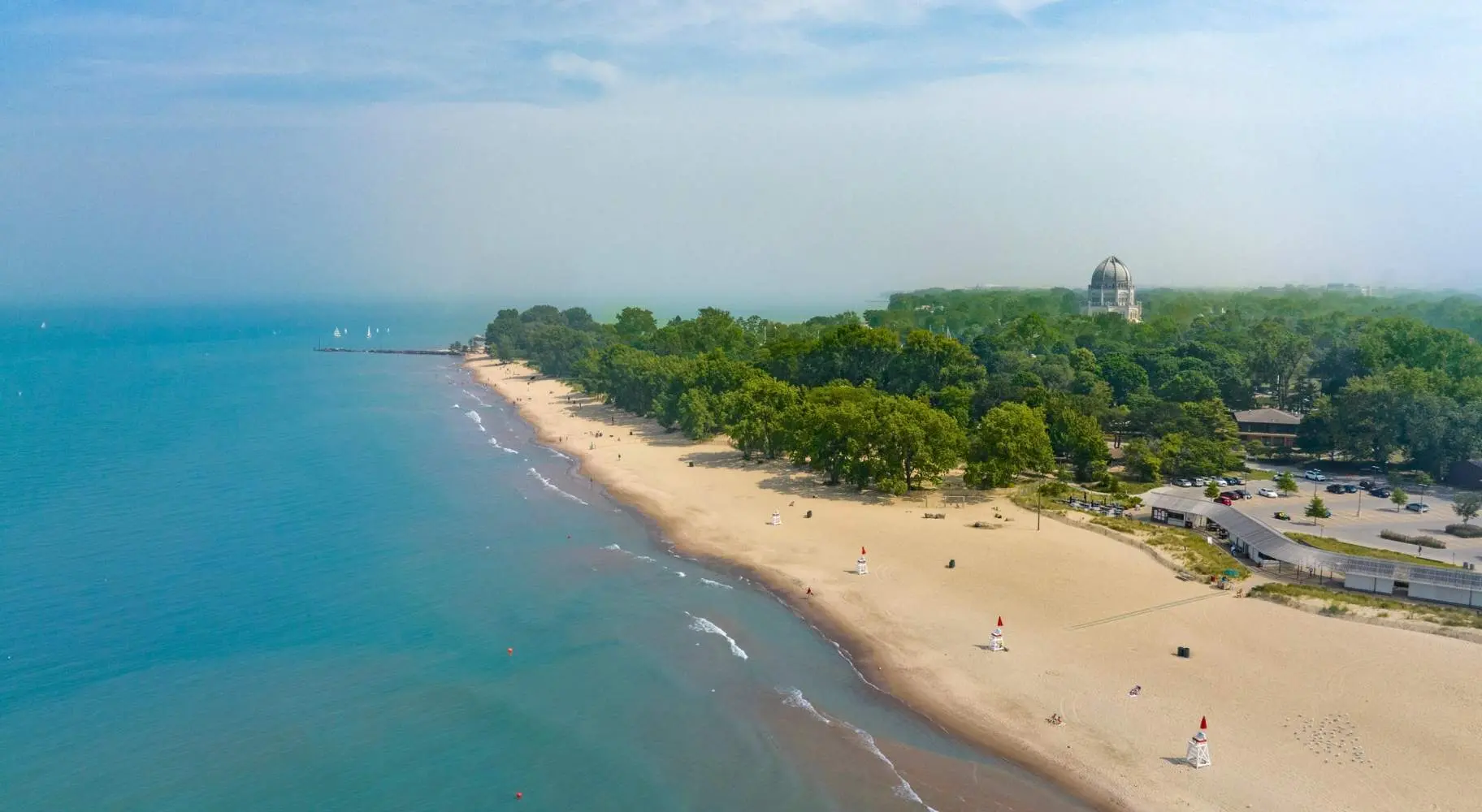 Una ripresa aerea del litorale di una spiaggia, con alberi verdi sullo sfondo