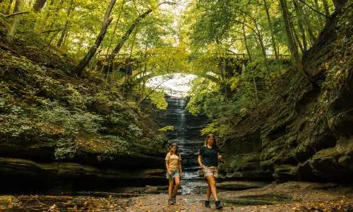 Due ragazze passeggiano davanti a una cascata nel Matthiessen State Park