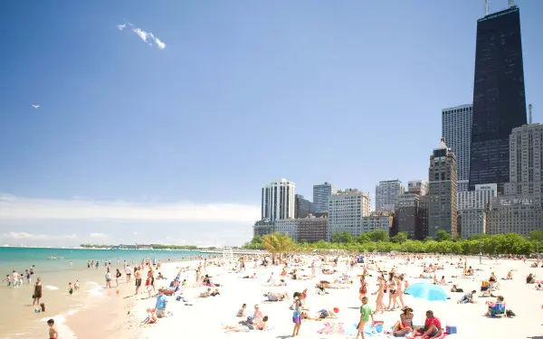 Folla di persone sulla spiaggia di Oak Street, a Chicago, in una giornata di sole. Sullo sfondo i grattacieli di Chicago.