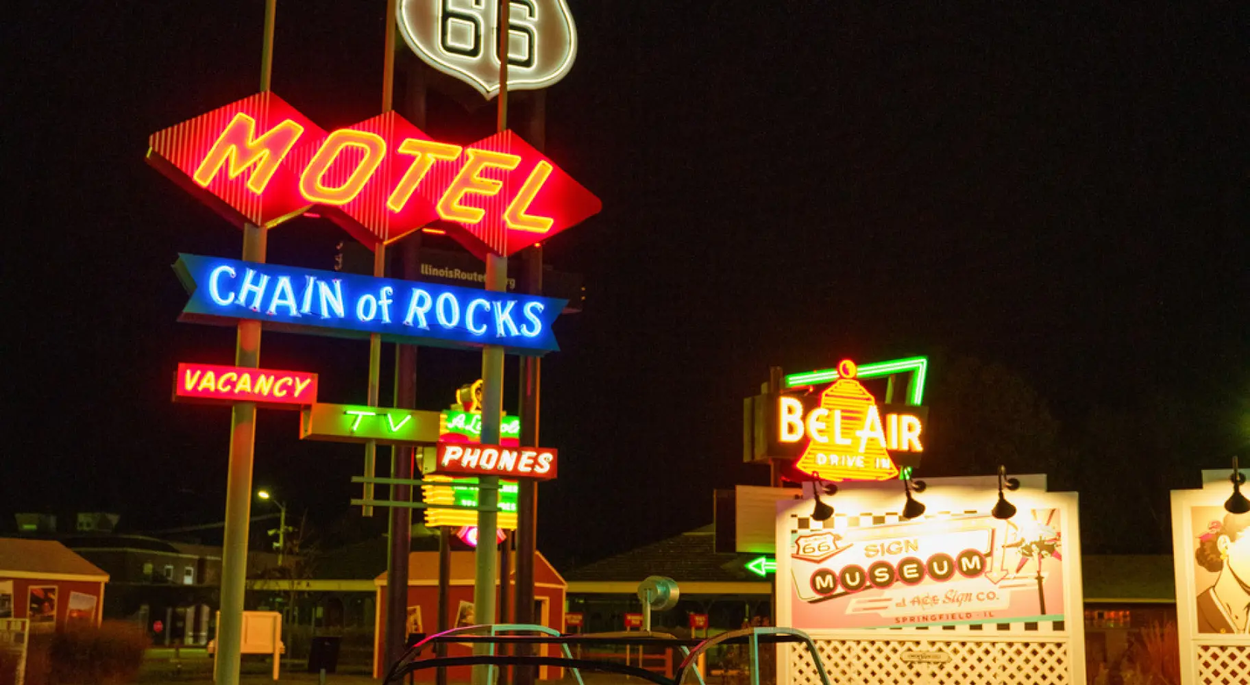 Insegne al neon d'epoca dei motel della Route 66 e una classica macchinina a pedali illuminate di notte.