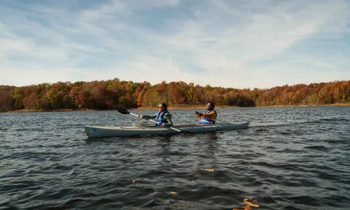 Due kayakisti su un lago con il fogliame autunnale lungo la riva.
