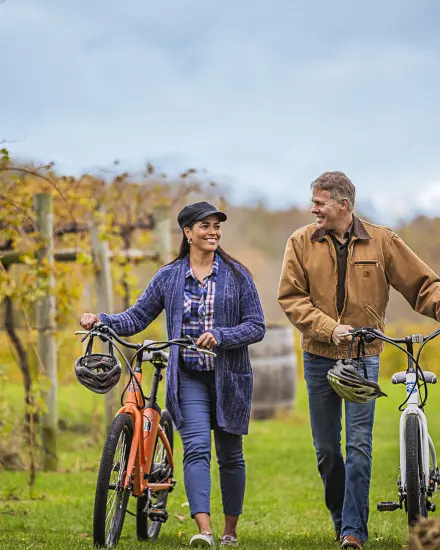 Una coppia a passeggio con la bicicletta tra le vigne