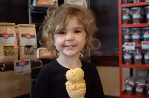 Un bambino piccolo si gode un cono gelato. 