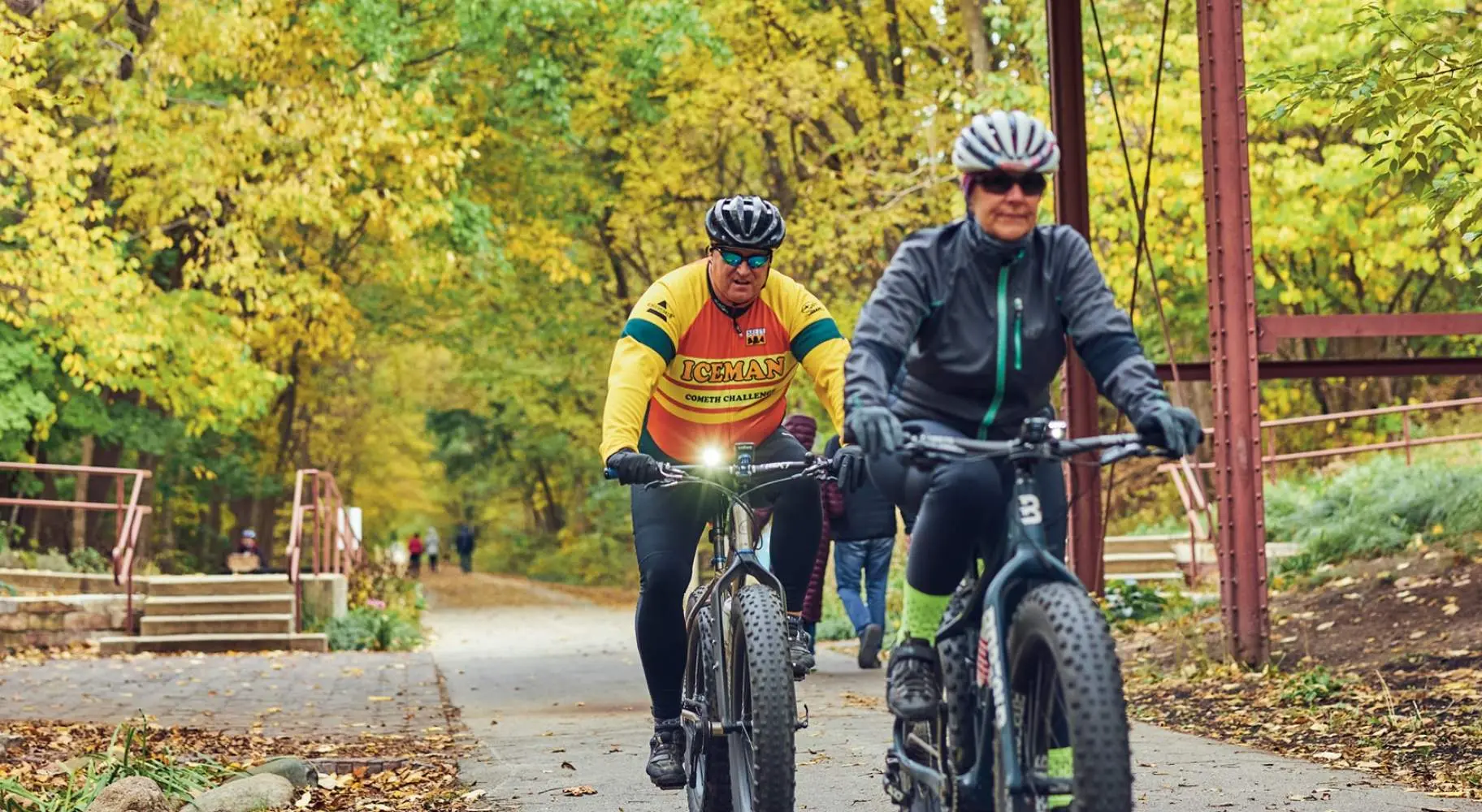 Due ciclisti che percorrono un sentiero boscoso sotto un vecchio ponte di legno