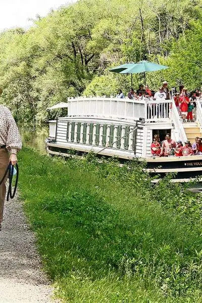 Una donna porta a spasso un cavallo lungo il canale mentre passa il battello dell'I&M canal