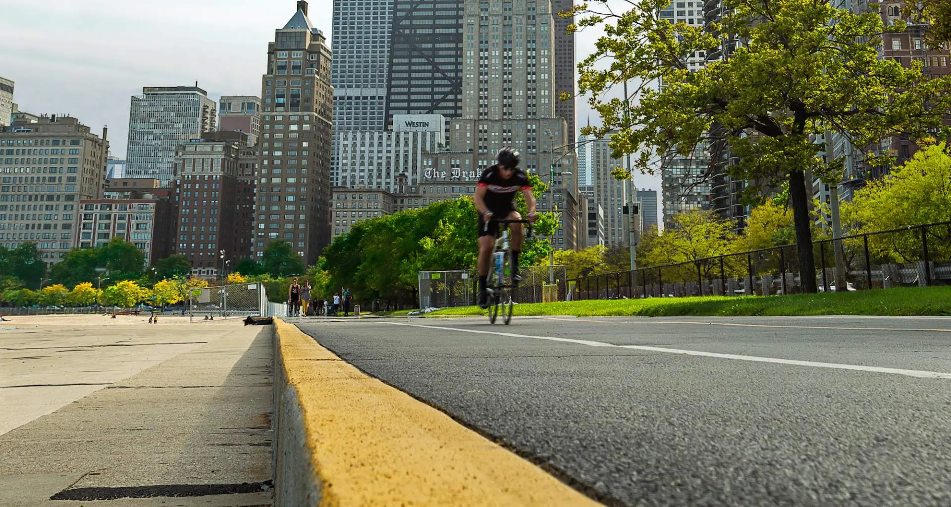 Ciclista su strada sulla pista ciclabile del lungolago di Chicago con la città sullo sfondo