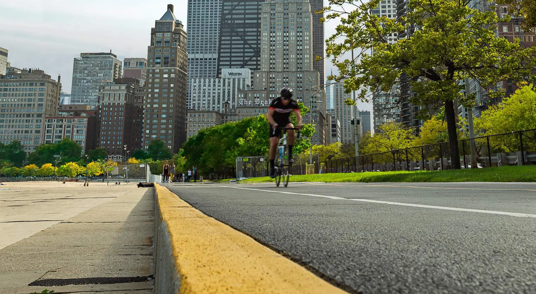 Ciclista su strada sulla pista ciclabile del lungolago di Chicago con la città sullo sfondo