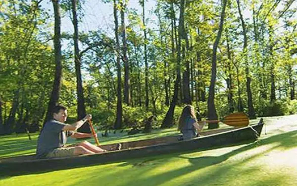 Immagine laterale di un padre e una figlia che percorrono un fiume paludoso in canoa