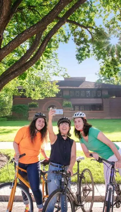 Persone in bicicletta in posa per una foto con casa sullo sfondo