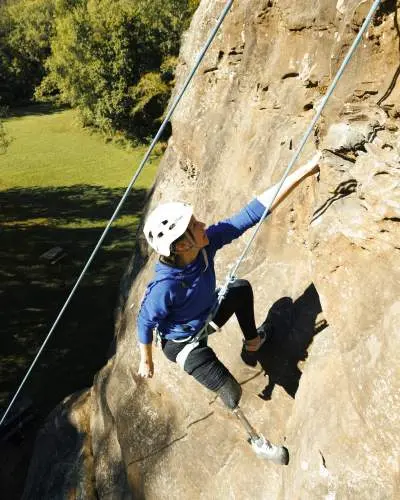 Un arrampicatore si cala con le mani da una roccia nel Giant City State Park