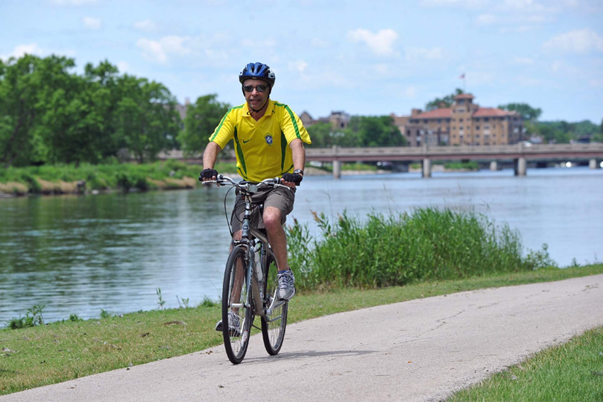 Un uomo con una camicia gialla brillante che pedala su un sentiero vicino al fiume Fox